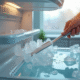 Personne grattant la glace dans un congélateur moderne